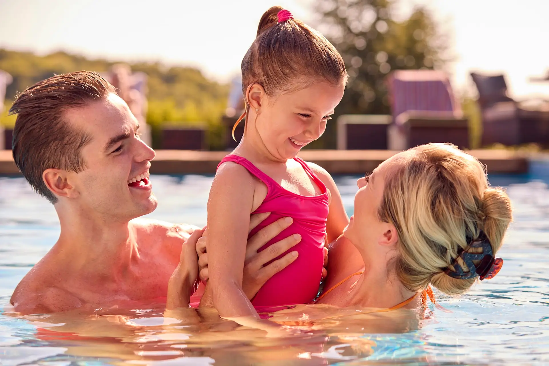 Smiling Family On Summer Holiday Relaxing In Swimming Pool